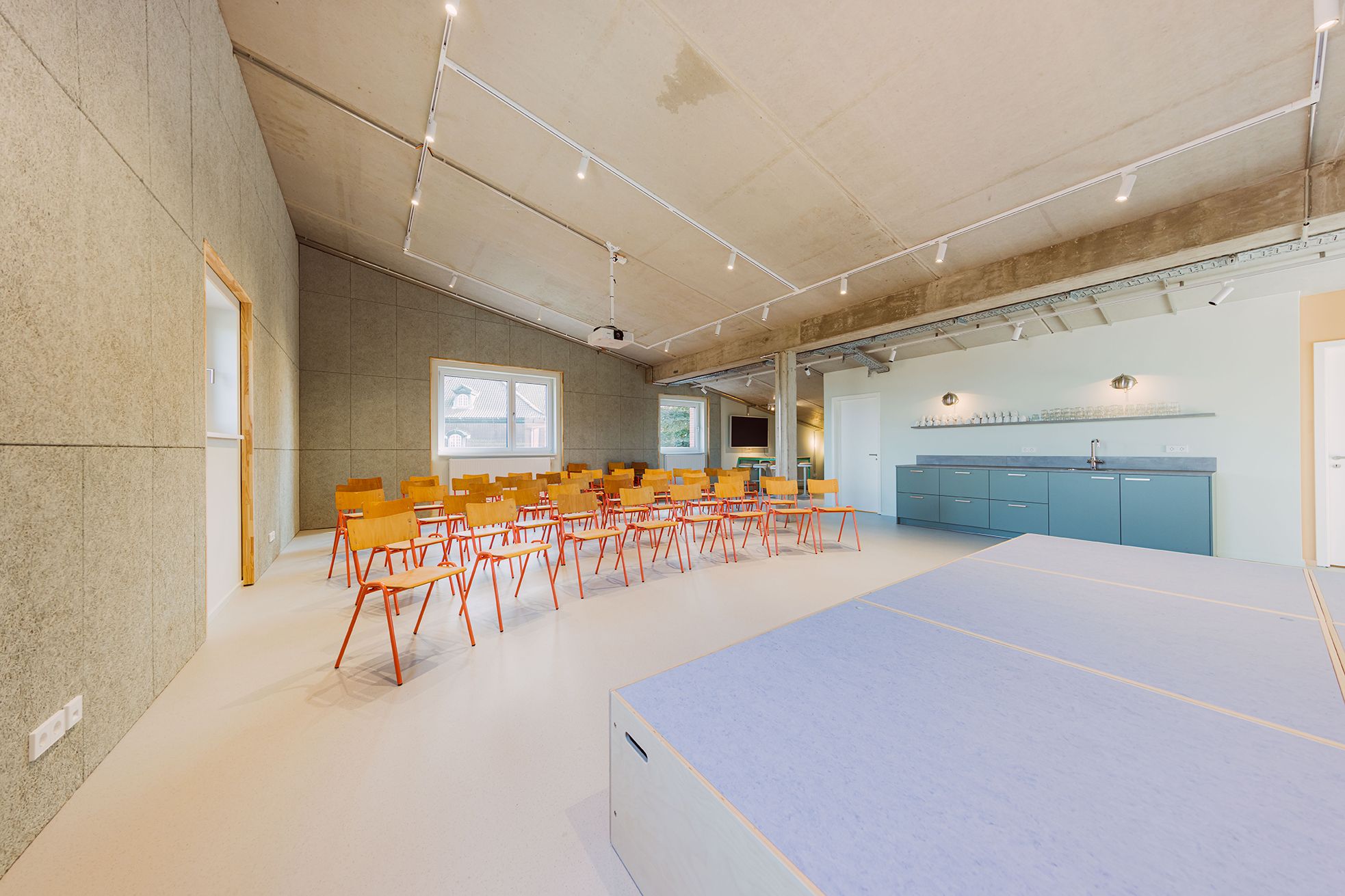 Heller Raum mit Bühne und Stühlen
